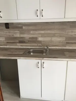 a kitchen counter with a sink and white cabinets at Family Hotel Argo in Varna City