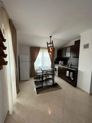 a living room with a table and a kitchen at PANTELI APART HOUSE in Aheloy