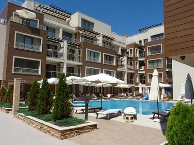 a pool in front of a building with umbrellas at Apartman Horizont II - side sea view in Sozopol