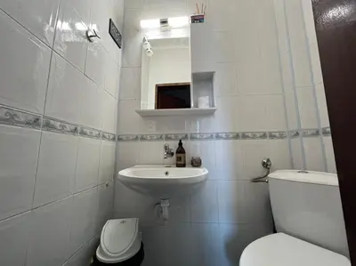 a white bathroom with a toilet and a sink at Izgrev Sarafovo in Burgas City