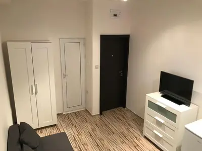 a living room with a tv and a dresser with a tvicterictericter at Студио Чайка Бургас Център in Burgas City