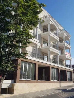 a white apartment building with balconies and a tree at MIDA Apartment in Obzor