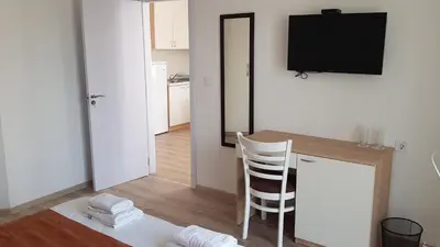 a living room with a table and a television on a wall at MIDA Apartment in Obzor