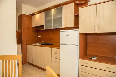 a kitchen with a white refrigerator and wooden cabinets at Prestige City 1BD Apt with POOL near to Cacao Beach by Flаt Manаger in Sunny Beach