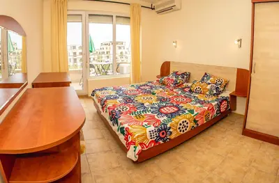 a bedroom with a bed and a table and a window at Prestige City 1BD Apt with POOL near to Cacao Beach by Flаt Manаger in Sunny Beach