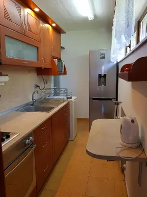 a kitchen with wooden cabinets and a stainless steel refrigerator at Апартамент Емилия in Sozopol