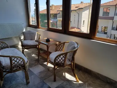a room with chairs and a table and windows at Апартамент Емилия in Sozopol