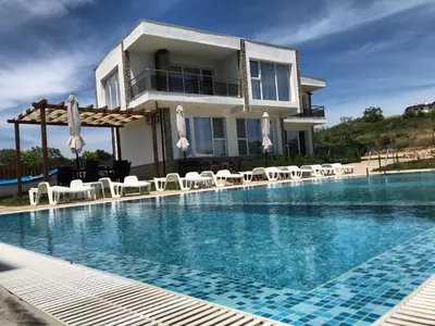 a villa with a swimming pool in front of a house at Ancient well in Sozopol