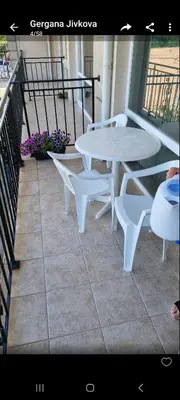a white table and benches on a balcony with flowers at Студия първа линия Черноморец in Chernomorets