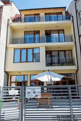 a building with an umbrella and a sign in front of it at Guest House Elidis in Primorsko