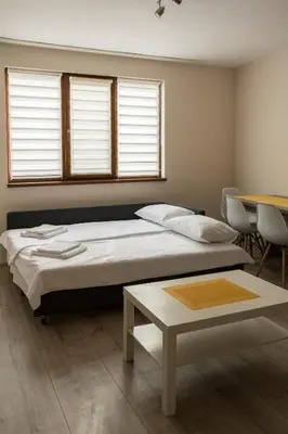 a bedroom with two beds and a table and windows at Margis Home in Burgas City
