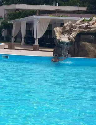 a person in a swimming pool with a water fountain at Apartment in Sunny beach, Complex Sun Village, 80 qm, 2 bedrooms & living room near to the beach, SWIMMING POOL, garden in Sunny Beach