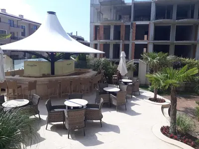 a patio with tables and chairs and a white umbrella at Menada Harmony Suites X in Burgas City