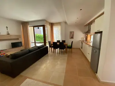 a living room with a black couch and a kitchen at Beautiful Sun Village with sea view in Byala