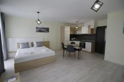 a bedroom with a bed and a table and a kitchen at La Familia Apartments in Varna City