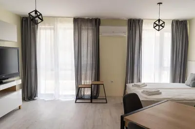 a bedroom with a bed and a tv and a table at La Familia Apartments in Varna City