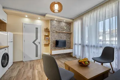 a living room with a television and a table and chairs at ROMANCE APARTAMENT & Free Parking in Burgas City