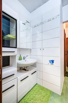 a bathroom with white cabinets and a sink and a green rug at Family Apartment - COMFORT IN THE CENTER in Burgas City