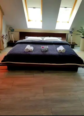 a bedroom with a large bed with a black comforter at Синьо лято in Burgas City
