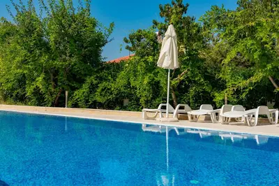 a swimming pool with chairs and an umbrella next to it at Menada Apolon Apartments in Sozopol