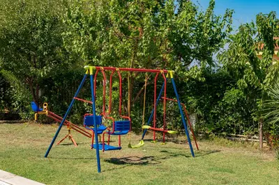 a playground with a swing set in a yard at Menada Apolon Apartments in Sozopol