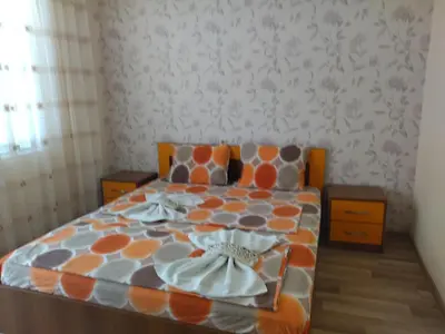 a bedroom with a bed with an orange and gray comforter at Фамилна къща Джоко in Kiten
