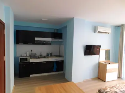 a kitchen with black cabinets and a blue wall at HomeLine Kazakovi in Nesebar