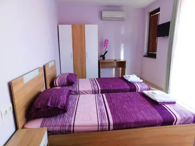 two beds in a room with purple sheets at HomeLine Kazakovi in Nesebar