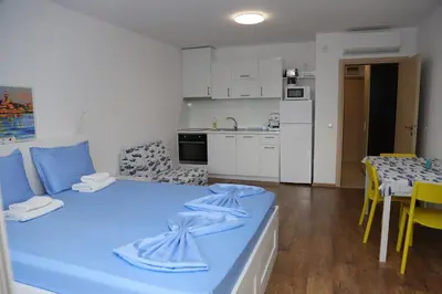 a living room with a blue bed and a kitchen at Lux Sozopoli Hills Apartments A19 и Studio А13 in Sozopol