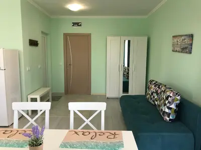 a living room with a blue couch and two white chairs at La MER 2 in Tsarevo