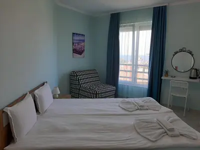 a bedroom with a bed with a chair and a window at La MER 2 in Tsarevo