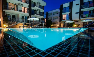 an empty swimming pool in front of buildings at night at Charming 1 Bedroom Apartment for up to 4 Guests in Sunny Beach