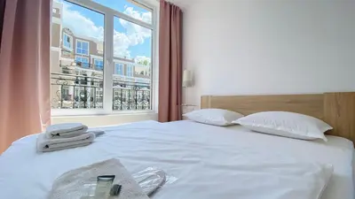 a white bed with a window with towels on it at APARTELLO Modern Apartments in DownPARK in Sunny Beach