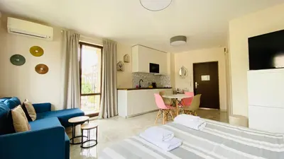 a living room with a blue couch and a kitchen at APARTELLO ARTUR - Modern Studios - Sveti Vlas in Sveti Vlas