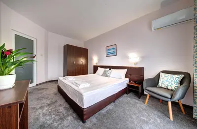 a hotel room with a bed and a chair at хотел Свети Николай Приморско in Primorsko