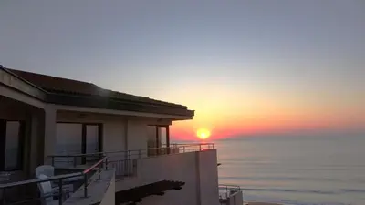 a house with the sunset in the background at Seafront Apartment im Obzor Beach Resort in Obzor