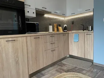 a kitchen with wooden cabinets and a black microwave at Briz MK Apartment in Ravda