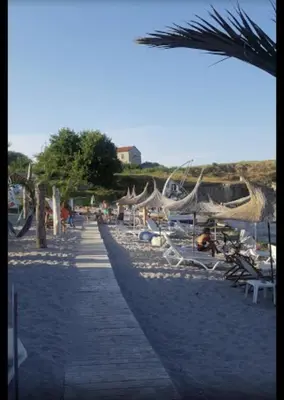 a beach with chairs and hammocks on the sand at Хотел Paradise in Tsarevo