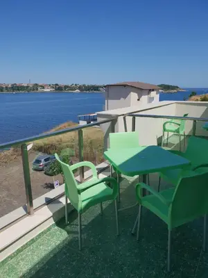 a patio with green chairs and a table on a balcony at Хотел Paradise in Tsarevo