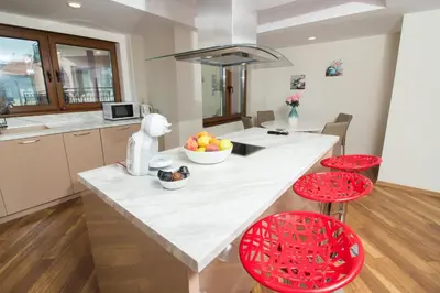 a kitchen with a large white counter and red stools at Breeze Guest House in Chernomorets