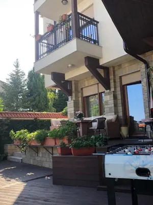 a building with a balcony with plants and a table at Breeze Guest House in Chernomorets