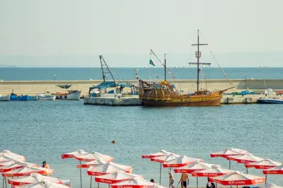 a group of red and white umbrellas and a boat in the water at Breeze Guest House in Chernomorets