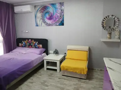 a bedroom with a bed and a chair and a mirror at PARUS-2-STUDIO in Pomorie