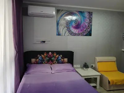 a bedroom with a purple bed and a painting on the wall at PARUS-2-STUDIO in Pomorie