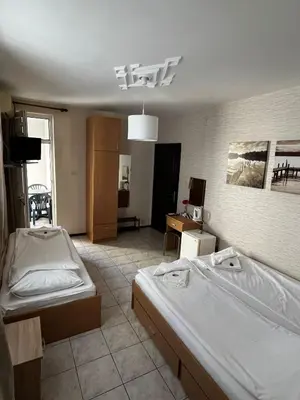 a bedroom with two beds and a room with a tv at Kъща за гости Христина in Lozenets