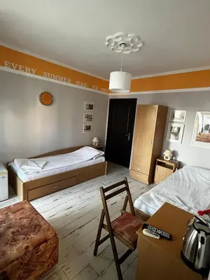 a bedroom with two beds and a table and a chair at Kъща за гости Христина in Lozenets