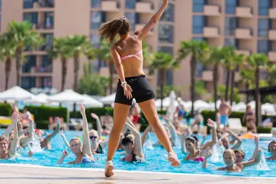 a woman standing in a swimming pool with a crowd of people at DIT Majestic Beach Resort in Sunny Beach