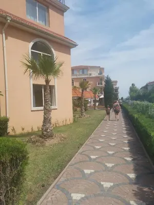 a group of people walking down a sidewalk next to a house at Hacienda Beach Apartment mit Meerblick in Sozopol