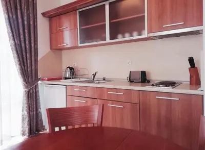 a kitchen with wooden cabinets and a sink and a table at Apart Hotel Efir in Sunny Beach