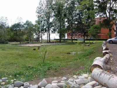 a fence with rocks and a field with a building at Apart Hotel Kasandra in Sunny Beach
